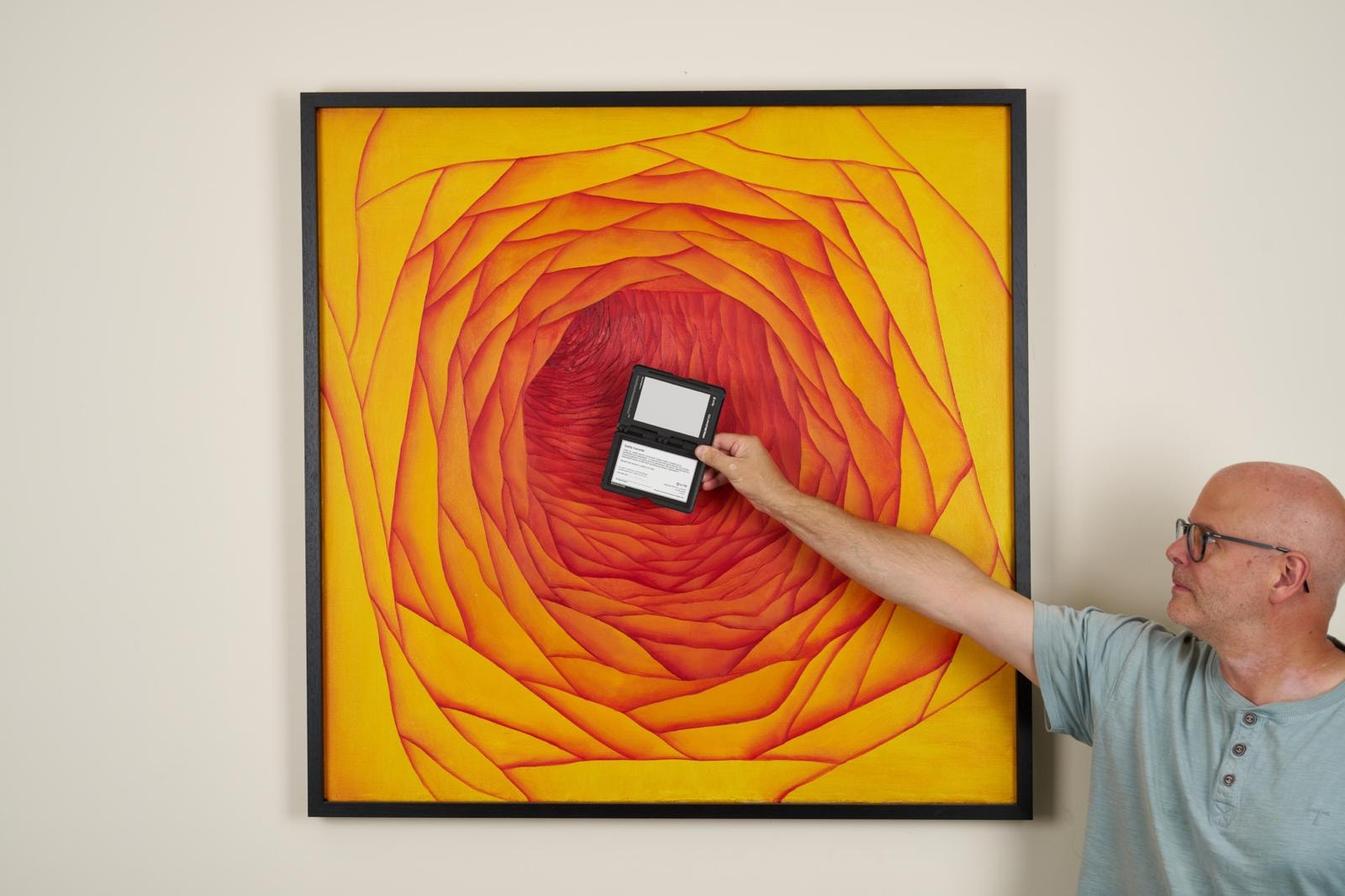 Man holding device near abstract spiral artwork