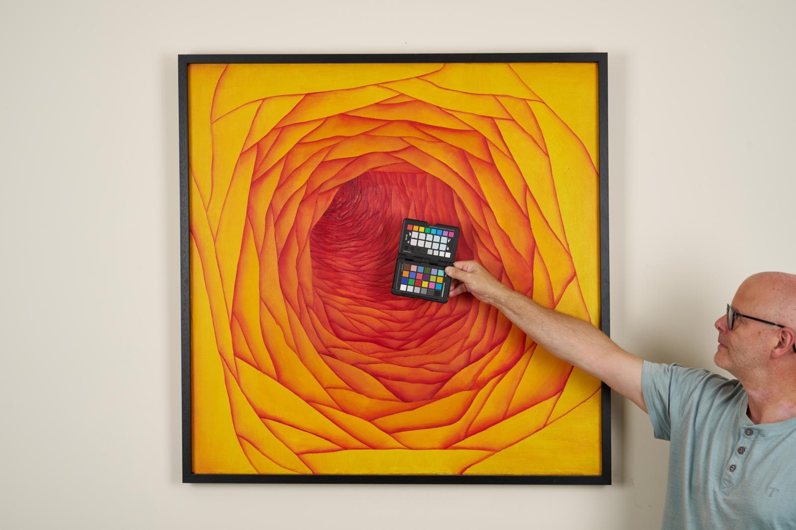 Man holding colour checker near spiral painting